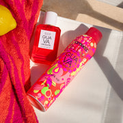 GUAVA GRANITA Eau de Parfum 50ml and Amika x Ellis Brooklyn GUAVA GRANITA Perk Up Dry Shampoo on white beach chair next to pink and orange beach towel and a lemon on a background of tan sand