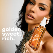 240mL bottle of Miss Amber Perfume Mist being held by a model with dark hair and a silver bejeweled top against a grey background with text on the left that reads 