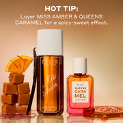 240mL bottle of Miss Amber Perfume Mist standing next to a 50mL bottle of Queens Caramel eau de parfum surrounded by caramel cubes, vanilla, an orange with red saffron pieces sticking out and pink salt with text that reads 