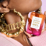 Close-up of woman wearing a pink sweater and gold hoop earrings that say 