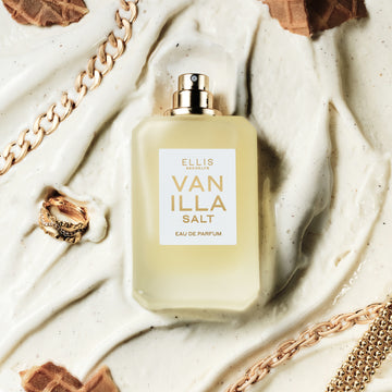 Vanilla Salt 50ml Eau De Parfum without cap in melted vanilla ice cream next to gold ring, gold bracelets, and pieces of ice cream cone. | english_image