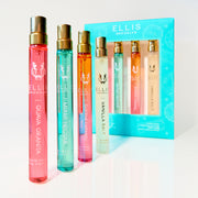 FIRST CLASS Gift Set containing GUAVA GRANITA Eau de Parfum 10ml, MIAMI NECTAR Eau de Parfum 10ml, QUEENS CARAMEL Eau de Parfum 10ml, and VANILLA SALT Eau de Parfum 10ml next to standing GUAVA GRANITA Eau de Parfum 10ml, MIAMI NECTAR Eau de Parfum 10ml, QUEENS CARAMEL Eau de Parfum 10ml, and VANILLA SALT Eau de Parfum 10ml all on a white surface and background