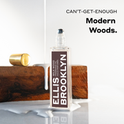 Milk Wood Fragrance Oil 15ml with cap removed in puddle of milk in front of piece of wood with milk being poured on it on white background below black text that reads 