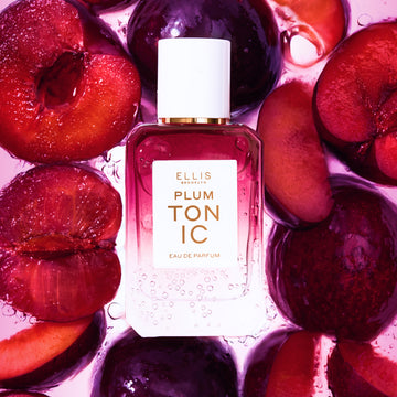 PLUM TONIC Eau de Parfum 50ml surrounded by sliced plums all under water with bubbles on a pink background | english_image