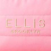 Gros plan sur une trousse de maquillage rose avec une broderie dorée qui indique « Ellis Brooklyn »