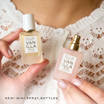 Vanilla Salt and Vanilla Rice Eau de Parfum 7.5mL mini spray bottles held in a women’s hands against a white knit sweater top, with black text in the bottom left corner that reads “NEW! MINI SPRAY BOTTLES.”