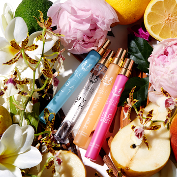 Salt 10ml Eau De Parfum Travel Spray,  Myth 10ml Eau De Parfum Travel Spray, Vanilla Milk 10ml Eau De Parfum Travel Spray, and Florist 10ml Eau De Parfum Travel Spray on white background surrounded by bergamot, lemons, pink flowers, white flowers, yellow flowers, pears, green leaves, sandal wood, and vanilla beans.