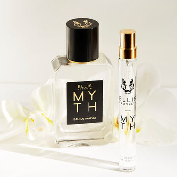 Myth 50ml Eau De Parfum and Myth 10ml Eau De Parfum Travel Spray in front of white flowers on white background.